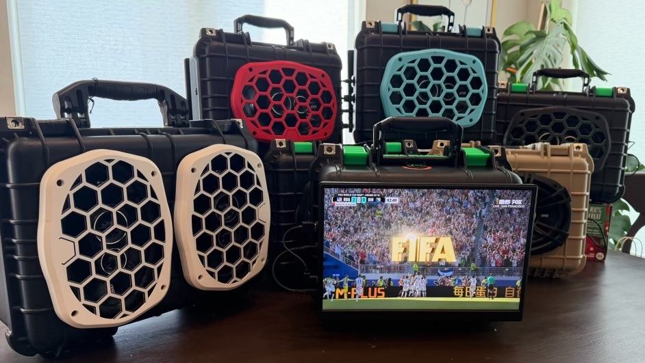 Lineup of TailgateTV cases in different colors, one open and playing a live soccer match on its screen